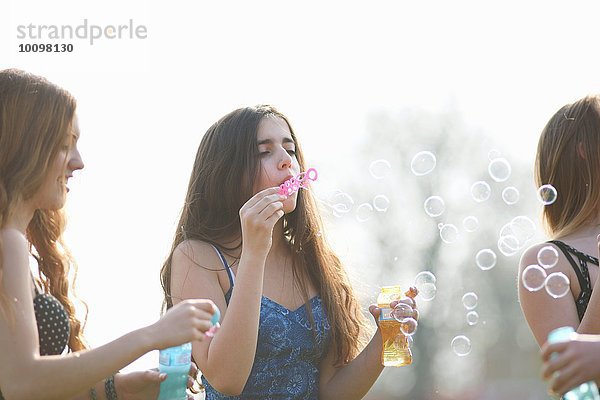 Drei Teenager-Mädchen  die im Park Blasen blasen.