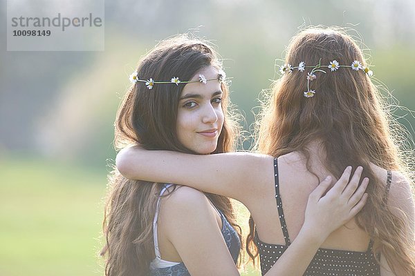 Rückansicht Porträt von zwei Teenager-Mädchen mit Gänseblümchen-Kopfbedeckung im Park