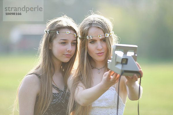 Zwei Teenager-Mädchen im Park mit Sofortbildkamera Selfie