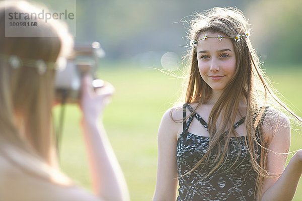 Teenagermädchen fotografiert beste Freundin mit Sofortbildkamera im Park