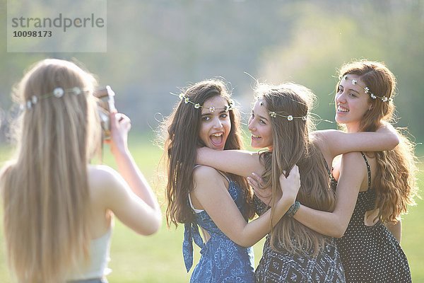 Teenagermädchen fotografiert drei Freunde mit Sofortbildkamera im Park