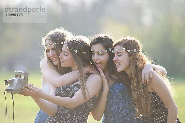 Vier Teenager-Mädchen im Park mit Sofortbildkamera Selfie