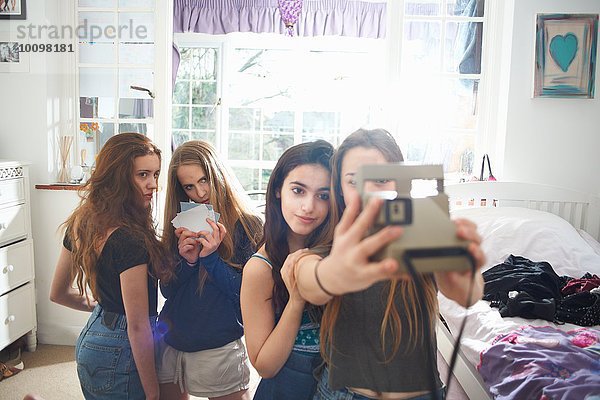 Vier Teenager-Mädchen im Schlafzimmer nehmen Instant Kamera Selfie