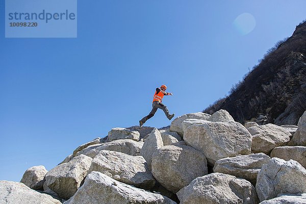 Arbeiter beim Springen auf Felsbrocken im Steinbruch