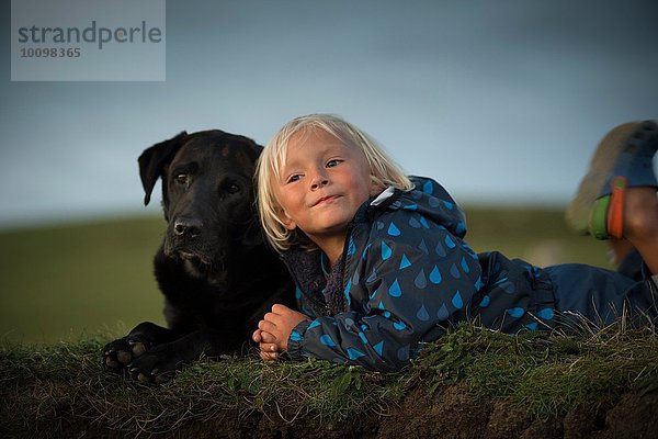 Junge im Liegen mit Hund im Feld