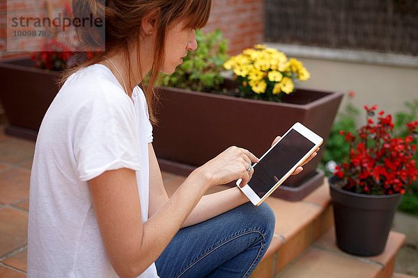 Seitenansicht der mittleren erwachsenen Frau im Freien mit Hilfe eines digitalen Tabletts