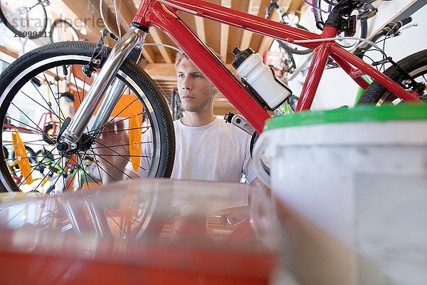 Mittlerer Erwachsener Mann in der Werkstatt  Blick durch den Fahrradrahmen