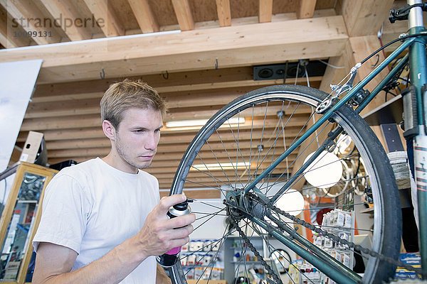 Mittlerer Erwachsener Mann in der Werkstatt  der das Fahrrad schmiert.