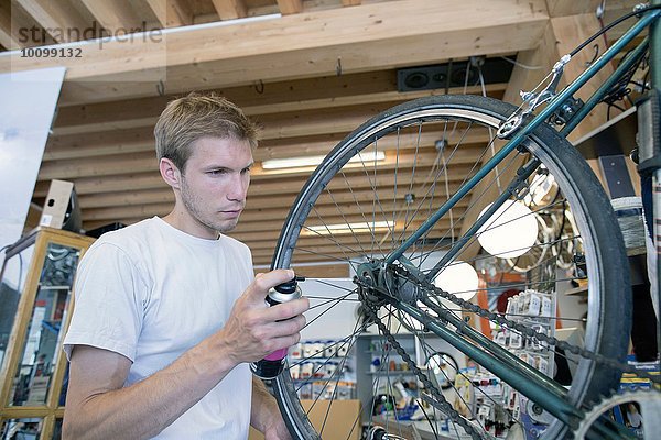 Mittlerer Erwachsener Mann in der Werkstatt  der das Fahrrad schmiert.