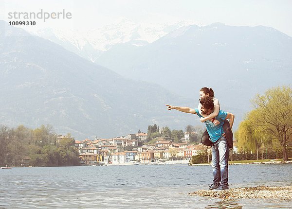 Junger Mann gibt Freundin Huckepack am Seeufer  Mergozzo-See  Verbania  Piemonte  Italien