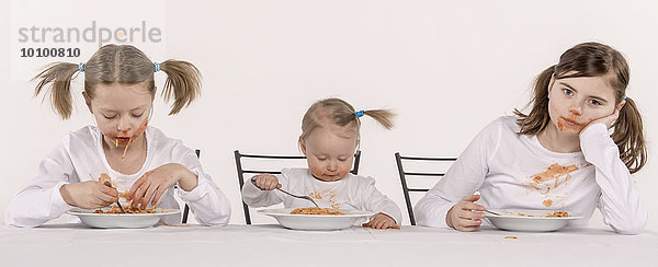 Drei Mädchen essen Spaghetti am Tisch
