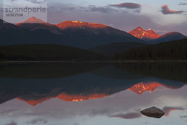 Berge  die sich bei Sonnenuntergang in einem See in den kanadischen Rocky Mountains spiegeln.