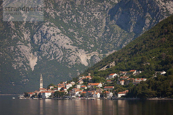 Blick über einen See auf ein Dorf an den Hängen eines Berges in Montenegro.
