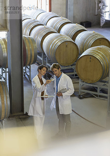 Winzer in Labormänteln untersuchen Wein im Weinkeller