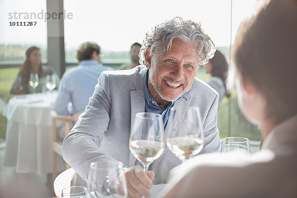 Lächelndes Paar trinkt Wein im sonnigen Restaurant