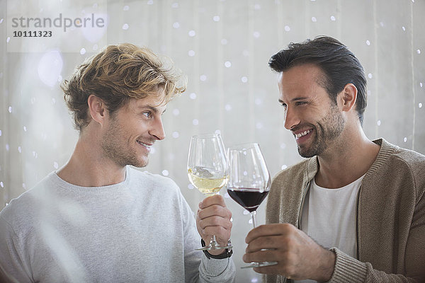 Lächelnde Männer stoßen auf Weingläser an