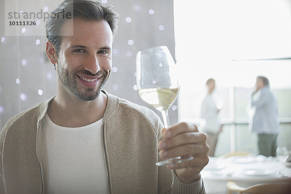 Portrait lächelnder Mann trinkt Weißwein im Restaurant