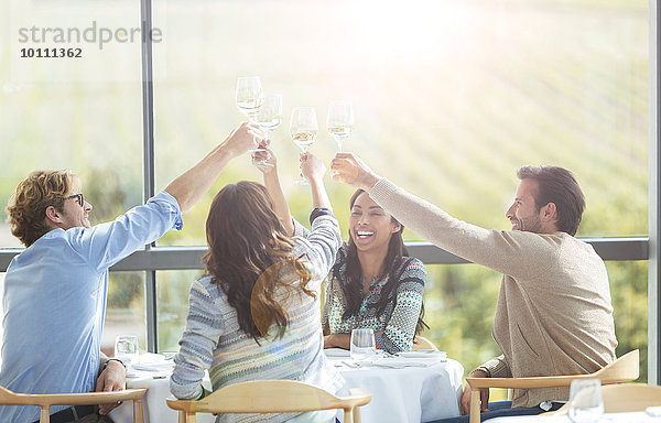 Freunde toasten Weingläser am Esstisch des Weingutes