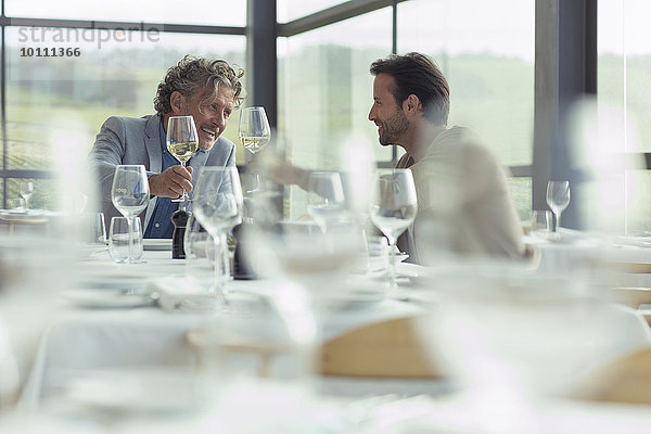 Männer toasten Weingläser am Restauranttisch