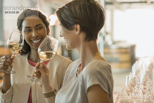 Lächelnde Frauen Weinverkostung Weißwein im Weinkeller