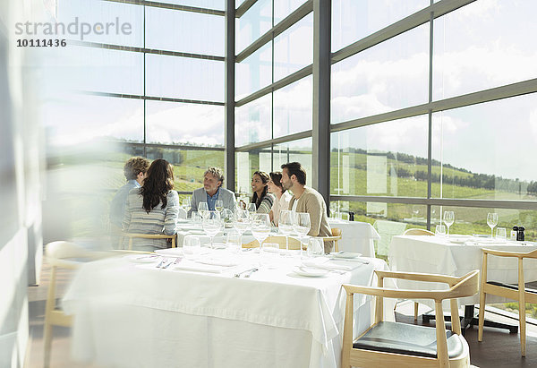 Freunde sitzen am Tisch im sonnigen Speisesaal des Weingutes