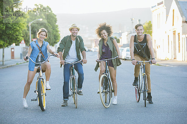 Portrait lächelnde Freunde sitzen auf Fahrrädern auf der Straße