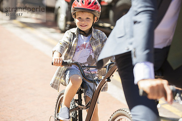 Portrait lächelnder Junge beim Radfahren auf sonniger Straße