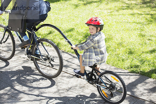 Junge auf Tandemfahrrad mit Geschäftsmann Vater im sonnigen Park