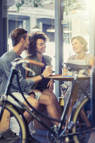 Freunde  die hinter dem Fahrrad am Kaffeetisch sitzen