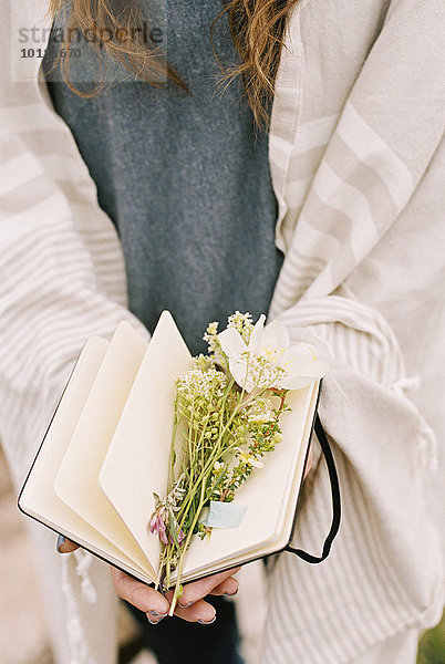 Seite Seiten Buchseite Buchseiten zwischen inmitten mitten liegend liegen liegt liegendes liegender liegende daliegen Frau Blume halten Close-up Notizblock ungestüm Notebook