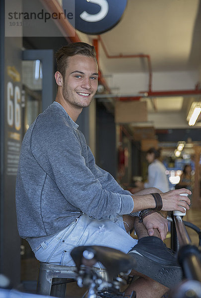 Portrait lächelnder junger Mann beim Kaffeetrinken im Café