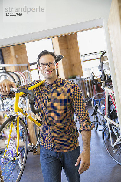 Portrait lächelnder Mann mit Brille und Fahrradträger im Fahrradgeschäft