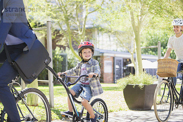 Portrait lächelnder Junge im Helm auf Tandemfahrrad mit Vater im Park