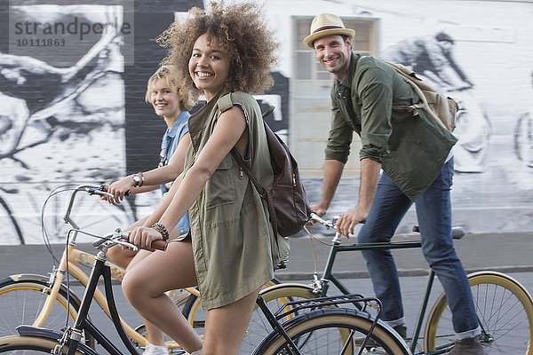 Portrait lächelnde Freunde beim Fahrradfahren in der Stadt