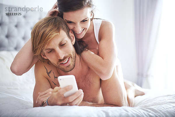 Paarverlegung auf dem Bett SMS mit Handy