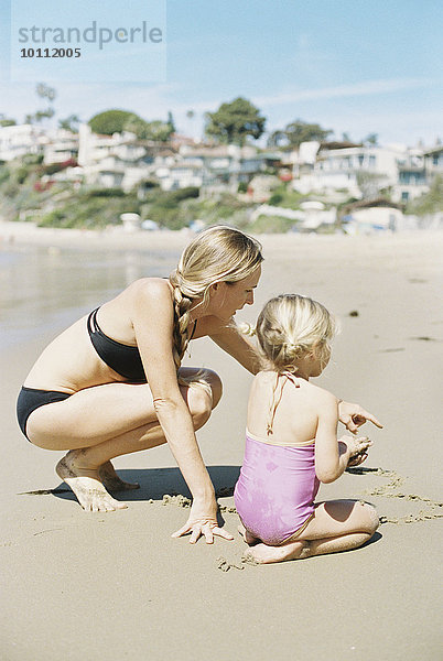 Frau Strand Bikini Sand Tochter spielen