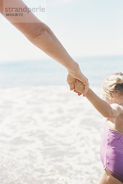 stehend Frau Strand Ozean halten Sand Tochter