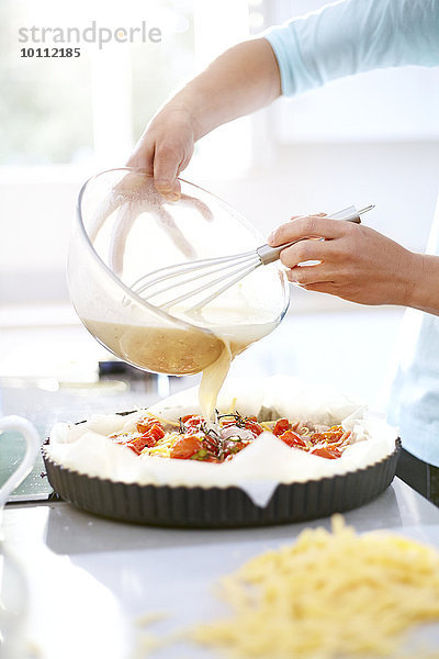 Frau bei der Zubereitung von Tomatenquiche in der Küche