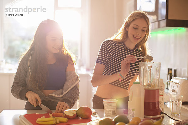 Teenagermädchen machen Smoothie in der sonnigen Küche