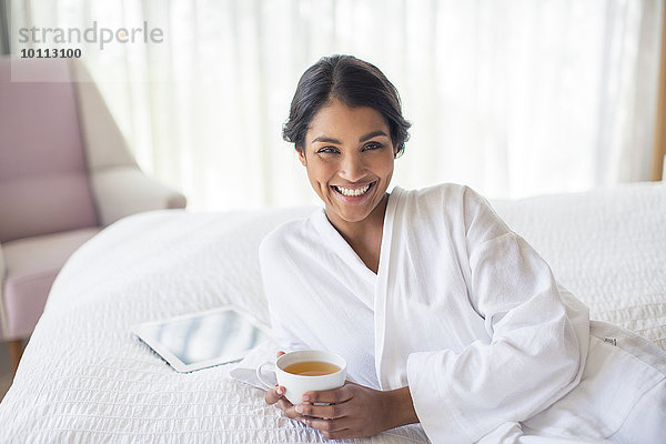 Portrait Frau lächeln Bett Bademantel trinken Tee