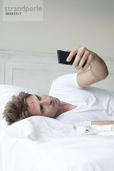 Mann mit Smartphone im Bett