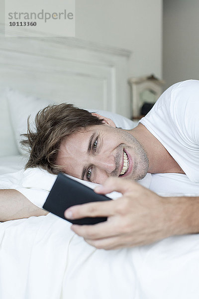 Mann im Bett mit Smartphone