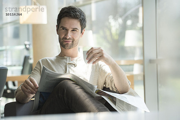 Mann entspannt mit Zeitung und Tasse Kaffee