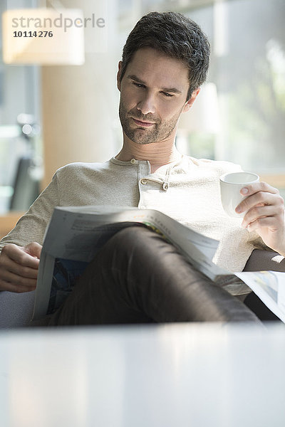 Mann liest Zeitung und trinkt Kaffee