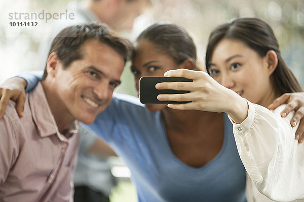 Frau fotografiert sich und ihre Freunde mit dem Smartphone