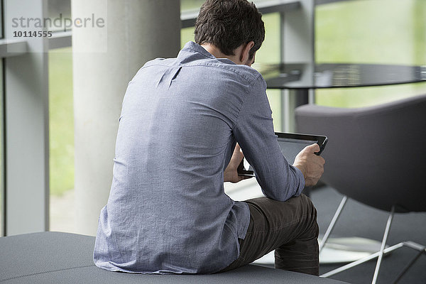 Mann allein sitzend  Blick auf digitales Tablett  Rückansicht
