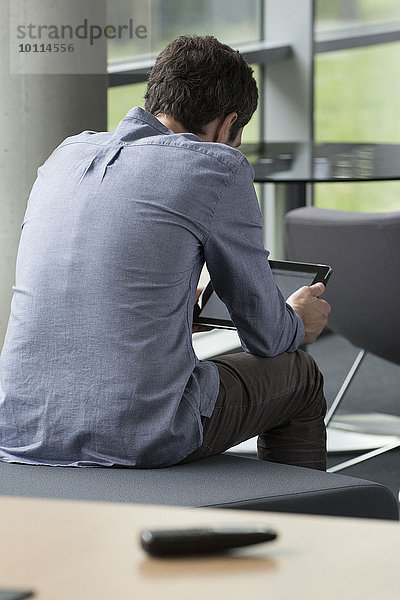 Mann mit digitalem Tablett allein zu Hause  Rückansicht