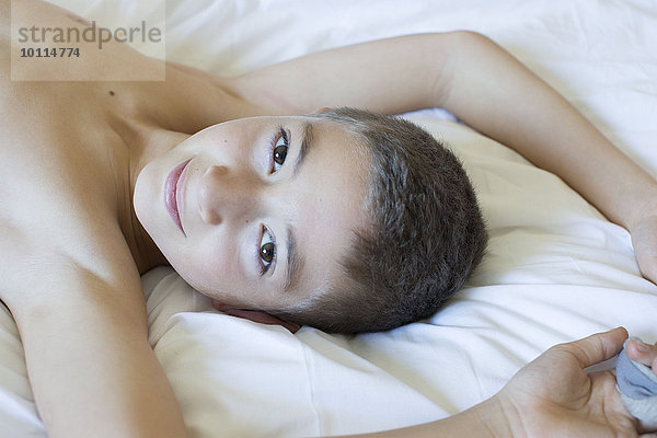 Junge auf dem Bett liegend  lächelnd  Portrait