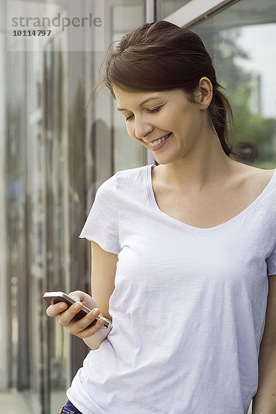 Frau mit Smartphone im Freien  lächelnd