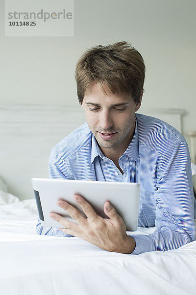 Mann im Bett liegend mit digitalem Tablett